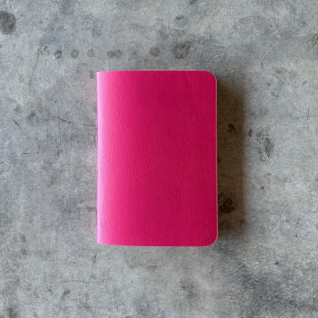 Pink notebook on a textured gray surface