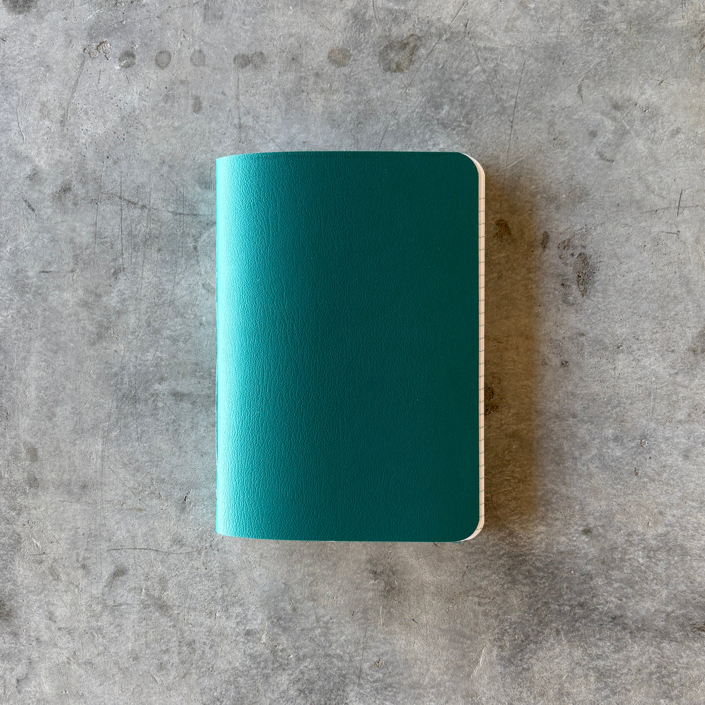 Teal notebook on a gray concrete surface